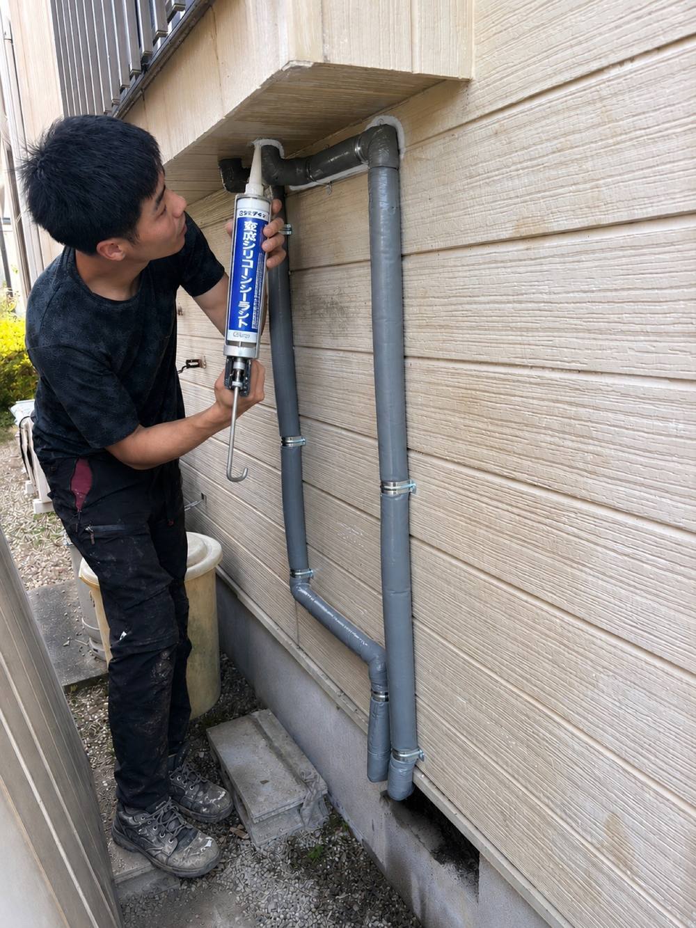 住宅外壁の配管接続部をシーリング材で防水処理する施工現場